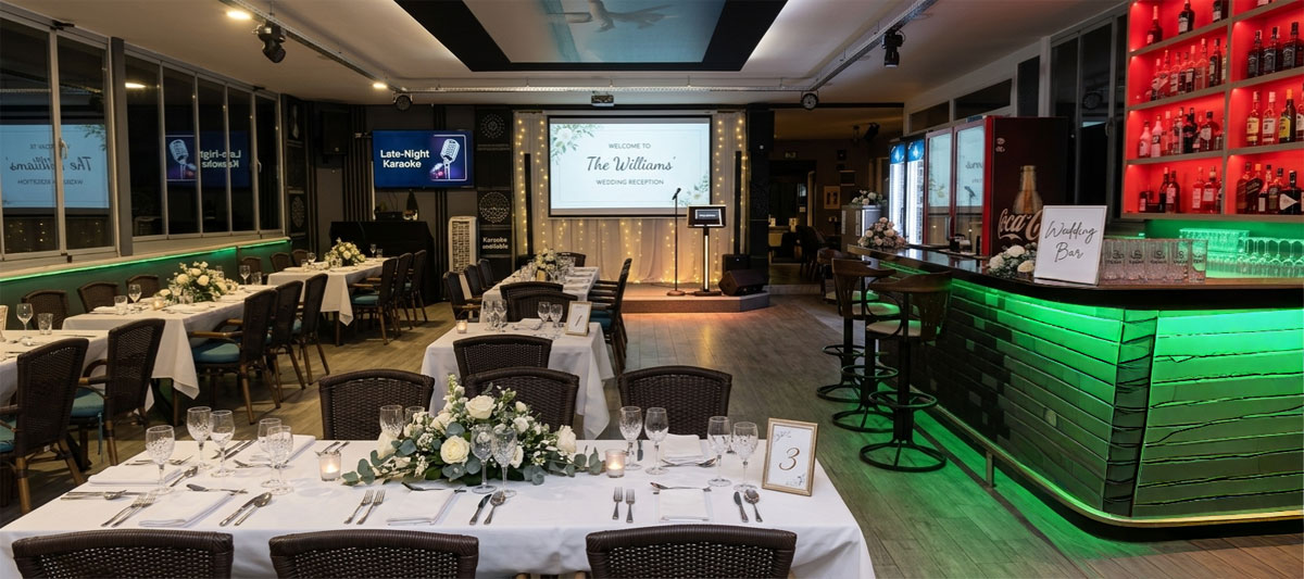 Private function room at Sarigerme Restaurant set up for a wedding reception with a stage and bar